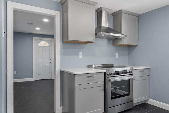 kitchen featuring stainless steel range with electric cooktop, dark tile patterned flooring, gray cabinetry, and wall chimney exhaust hood