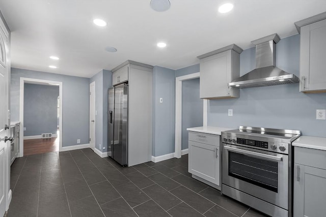 kitchen featuring stainless steel appliances, dark tile patterned floors, wall chimney range hood, and gray cabinets