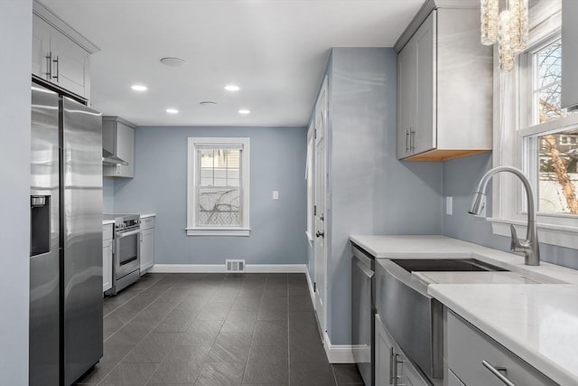 kitchen featuring sink, stainless steel appliances, wall chimney range hood, and gray cabinets