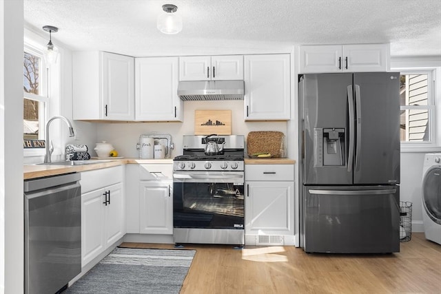 kitchen featuring under cabinet range hood, white cabinets, light countertops, appliances with stainless steel finishes, and washer / clothes dryer