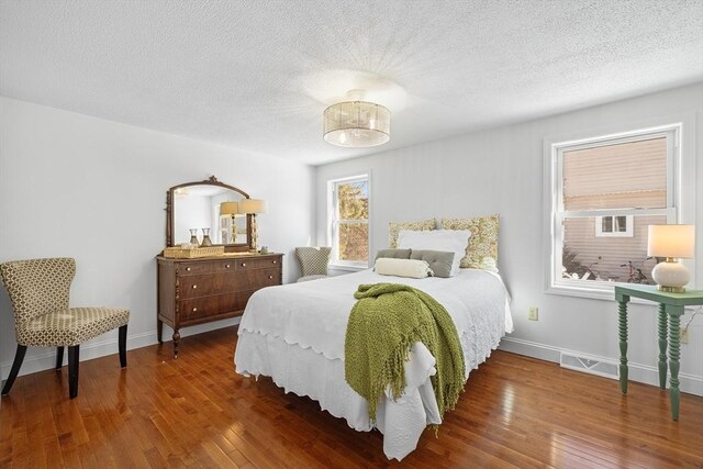 bedroom with a textured ceiling, baseboards, and dark wood-type flooring