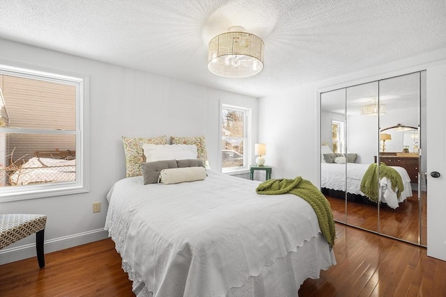 bedroom with a closet, baseboards, a textured ceiling, and hardwood / wood-style floors