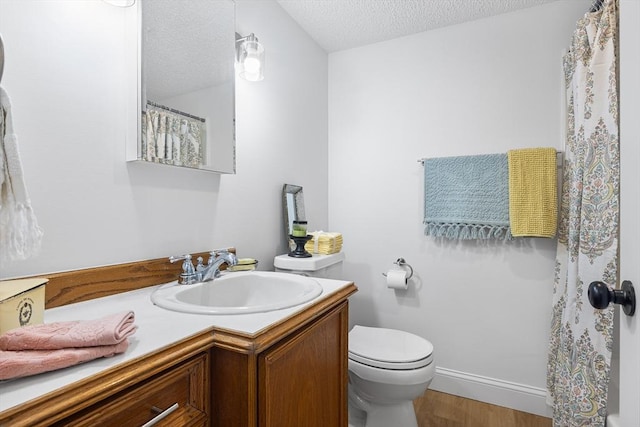 bathroom featuring baseboards, toilet, wood finished floors, a textured ceiling, and vanity