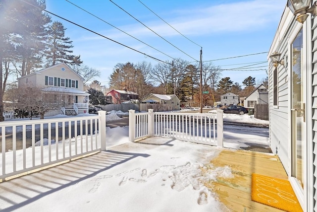 snow covered patio featuring a residential view and fence