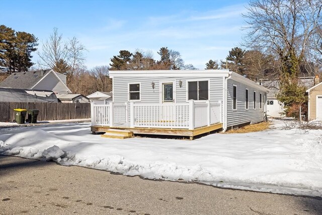 snow covered back of property featuring fence and a deck