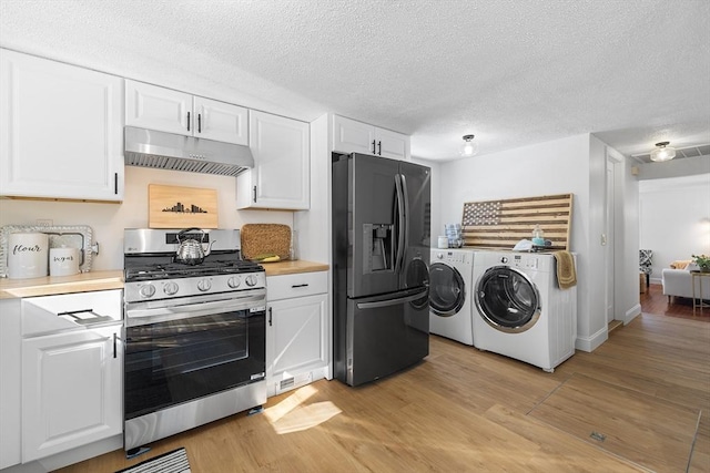 kitchen with light countertops, black refrigerator with ice dispenser, gas range, independent washer and dryer, and under cabinet range hood