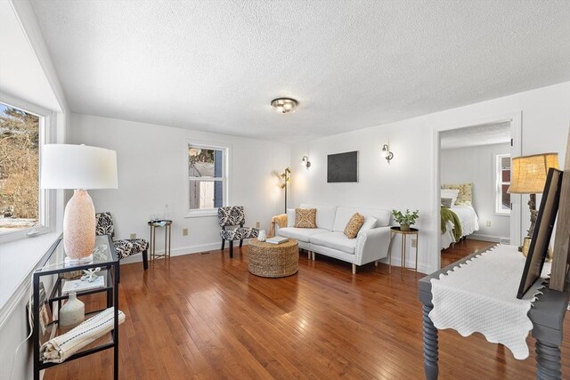 living room with baseboards, a textured ceiling, and hardwood / wood-style floors