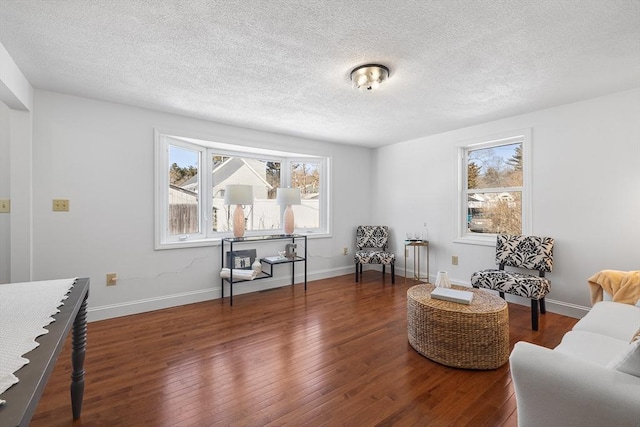 sitting room with dark wood-style flooring, a textured ceiling, and baseboards