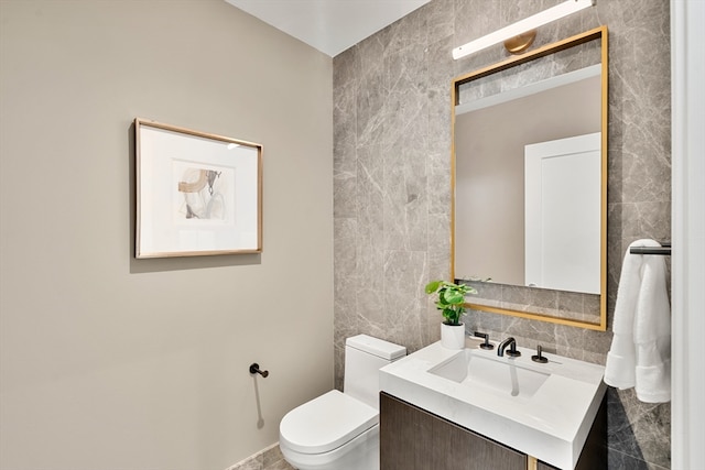 bathroom with vanity, toilet, and tile walls