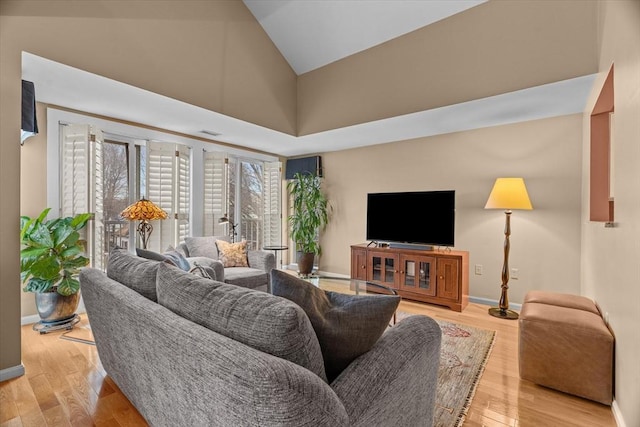 living room featuring high vaulted ceiling and light hardwood / wood-style flooring