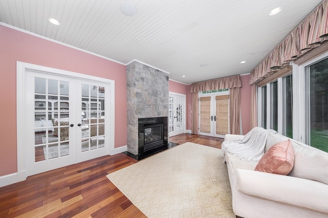 living room with french doors, crown molding, wood-type flooring, and a large fireplace