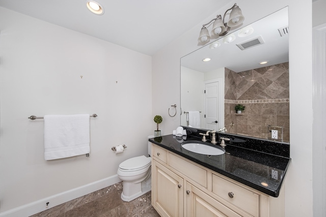 bathroom featuring vanity, a tile shower, and toilet