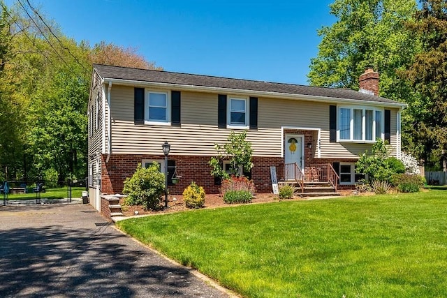 bi-level home featuring a chimney and brick siding