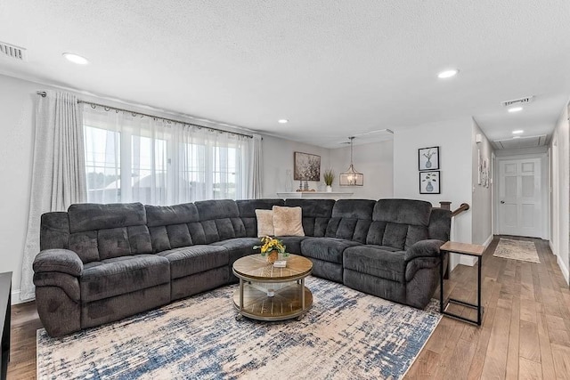 living room with hardwood / wood-style flooring, a textured ceiling, and recessed lighting