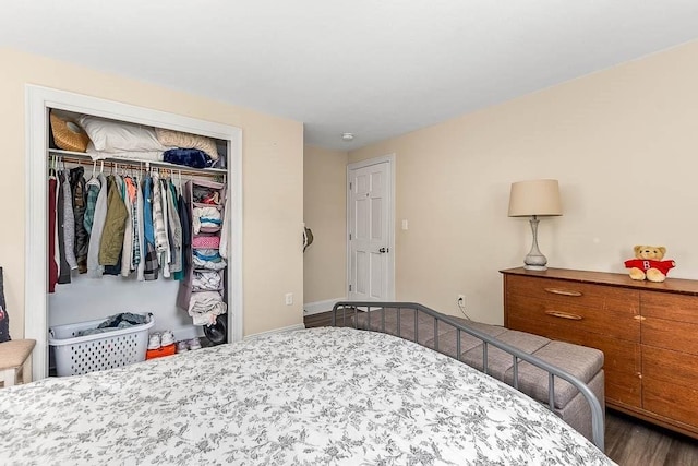 bedroom with a closet, dark wood-type flooring, and baseboards
