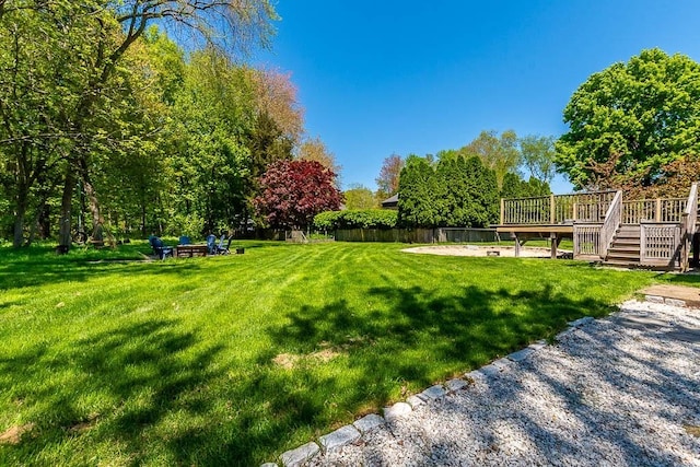 view of green lawn with a deck and stairs