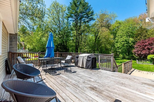 wooden terrace with outdoor dining space and area for grilling