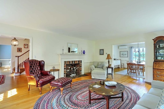 47 Fallon Dr, Westport, MA 02790 - living room featuring light wood-style flooring, a wall mounted AC, a chandelier, and stairway