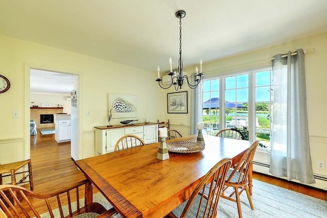 47 Fallon Dr, Westport, MA 02790 - dining room featuring light wood-style flooring, a chandelier, baseboard heating, and a fireplace