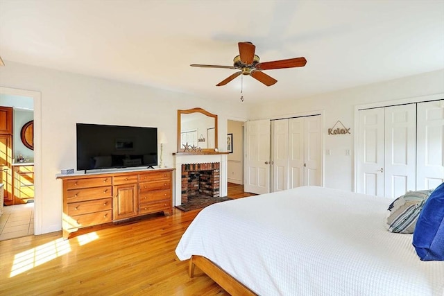 47 Fallon Dr, Westport, MA 02790 - bedroom with two closets, light wood-type flooring, ceiling fan, and a brick fireplace