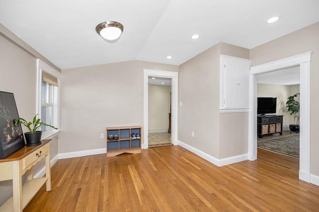 interior space featuring lofted ceiling, light wood-style floors, and baseboards