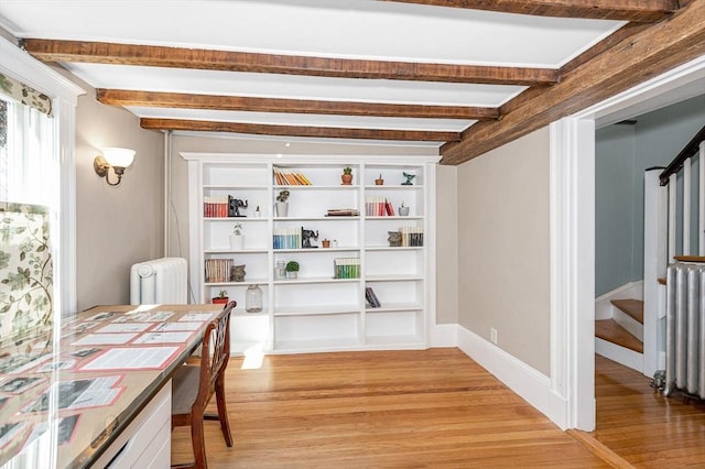 interior space featuring light wood-type flooring, radiator, beamed ceiling, and stairway