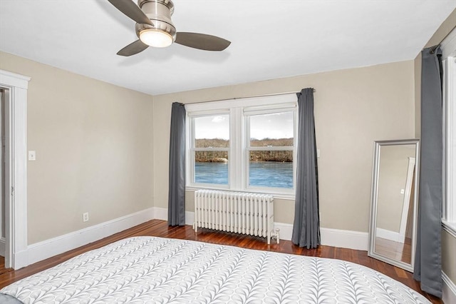 unfurnished bedroom featuring baseboards, radiator, wood finished floors, and a ceiling fan