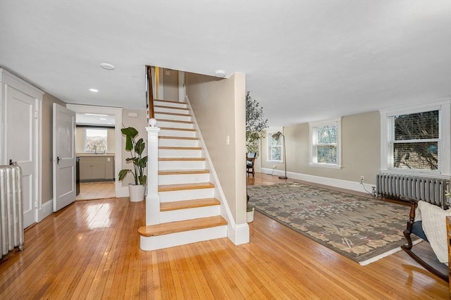 stairs with hardwood / wood-style flooring, radiator heating unit, and a wealth of natural light