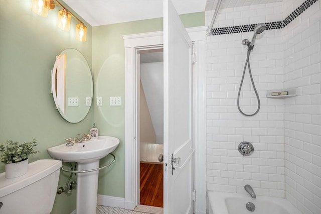 bathroom featuring a sink, baseboards, toilet, and shower / tub combination