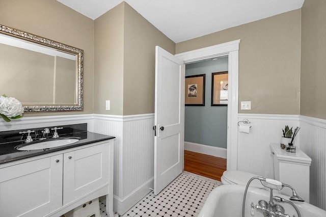 bathroom with a wainscoted wall, a tub, and vanity