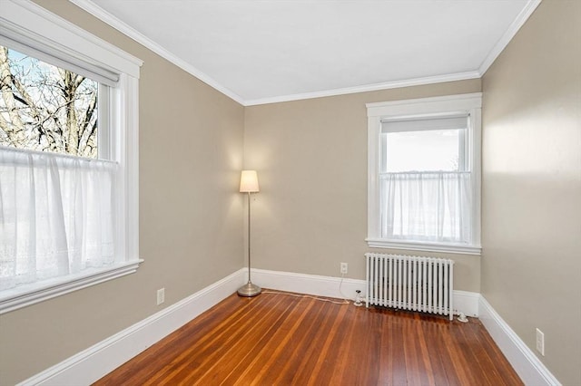 spare room featuring ornamental molding, radiator heating unit, baseboards, and wood finished floors