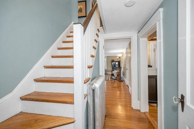 stairway featuring wood finished floors and radiator heating unit