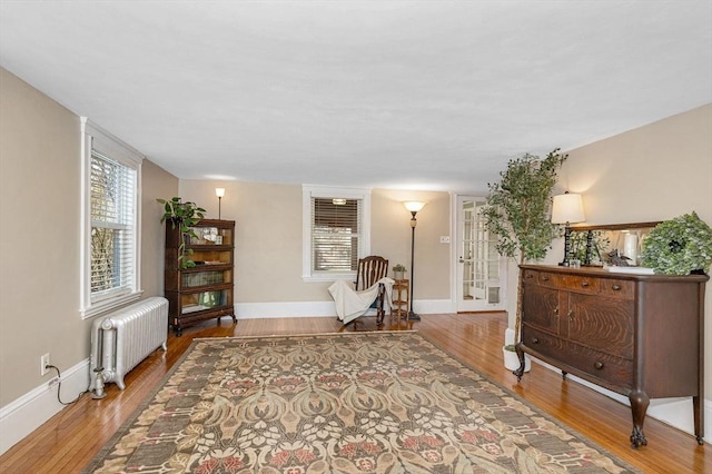 living area featuring radiator heating unit, baseboards, and wood finished floors