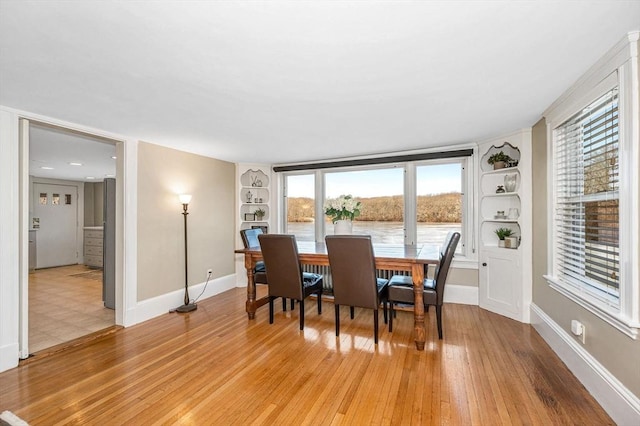 dining room featuring built in features, light wood-type flooring, and baseboards