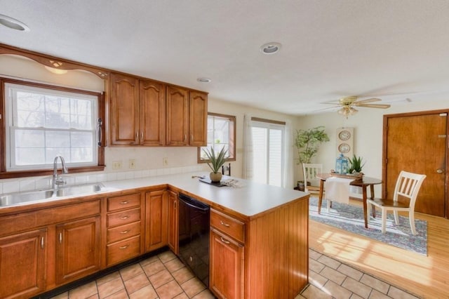 kitchen with plenty of natural light, dishwasher, sink, and kitchen peninsula