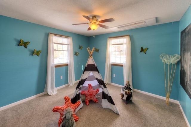 rec room with ceiling fan, carpet floors, a wealth of natural light, and a textured ceiling