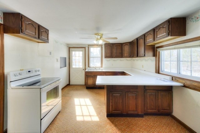 kitchen with sink, ceiling fan, dark brown cabinetry, white electric stove, and kitchen peninsula