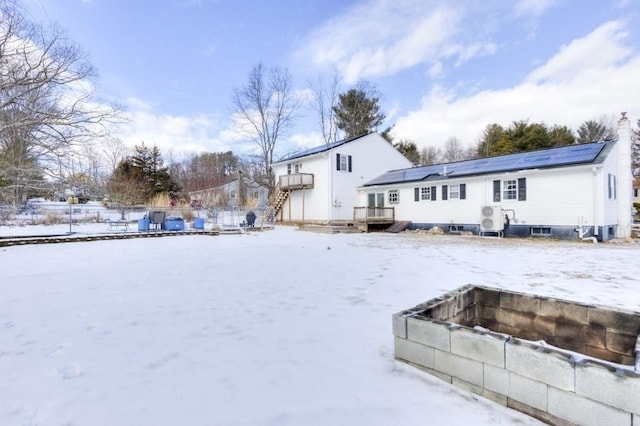 snow covered house featuring a deck and solar panels