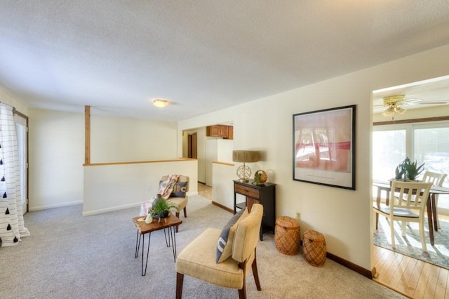 living room with light carpet, ceiling fan, and a textured ceiling