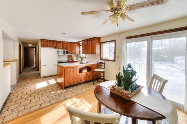 kitchen with white refrigerator, ceiling fan, light hardwood / wood-style floors, and kitchen peninsula