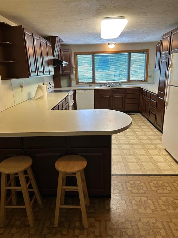 211 Stevens St, Marlborough, MA 01752 - kitchen featuring white appliances, light flooring, plenty of natural light, a peninsula, and a textured ceiling