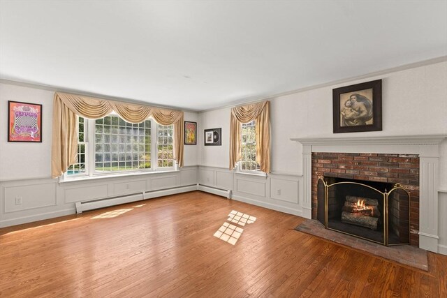 7 Stoney Hill Rd, Mattapoisett, MA 02739 - unfurnished living room with a brick fireplace, wood finished floors, a baseboard heating unit, a wainscoted wall, and crown molding