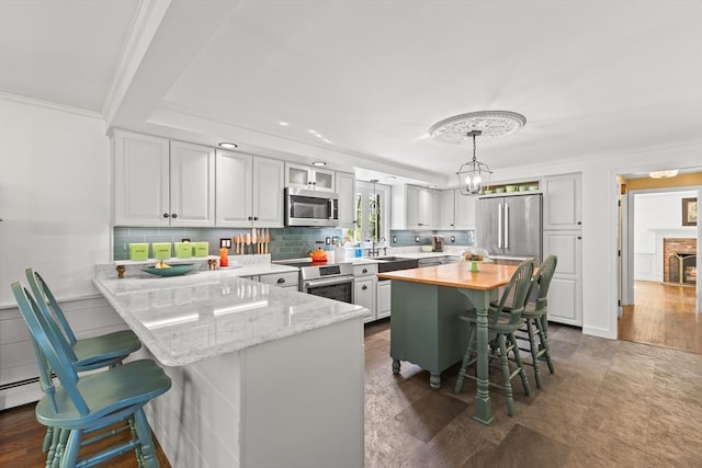 7 Stoney Hill Rd, Mattapoisett, MA 02739 - kitchen with appliances with stainless steel finishes, a kitchen breakfast bar, a peninsula, ornamental molding, and decorative backsplash