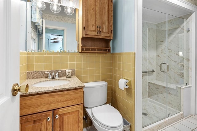 bathroom with vanity, tile walls, toilet, and a marble finish shower