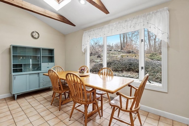 dining space with baseboards, lofted ceiling with skylight, and light tile patterned flooring