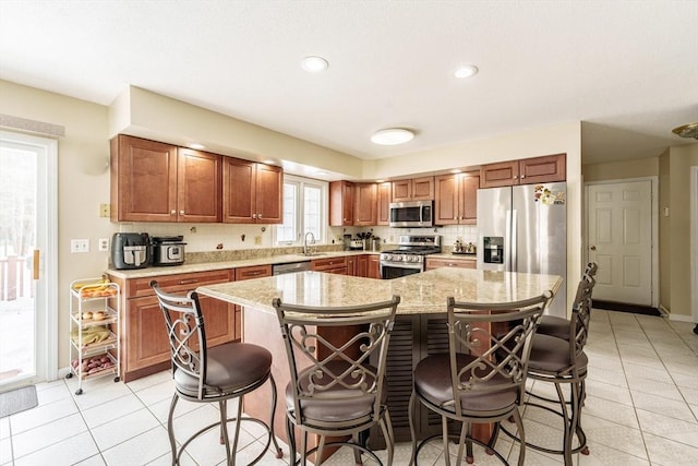 kitchen featuring light tile patterned floors, a kitchen bar, a kitchen island, and appliances with stainless steel finishes