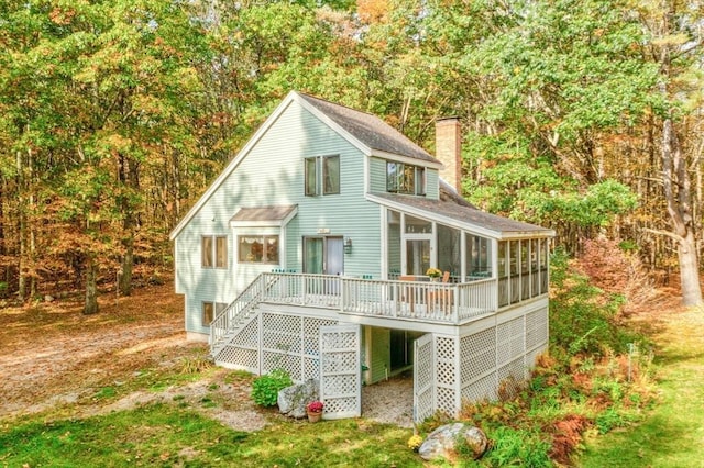 back of property with stairs, a deck, a sunroom, and a chimney