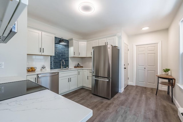 kitchen with appliances with stainless steel finishes, sink, white cabinets, backsplash, and light hardwood / wood-style flooring