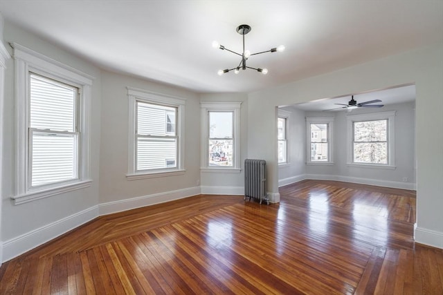 empty room featuring dark wood-type flooring, radiator heating unit, and a chandelier