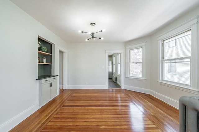 interior space featuring built in shelves, wood-type flooring, and a chandelier